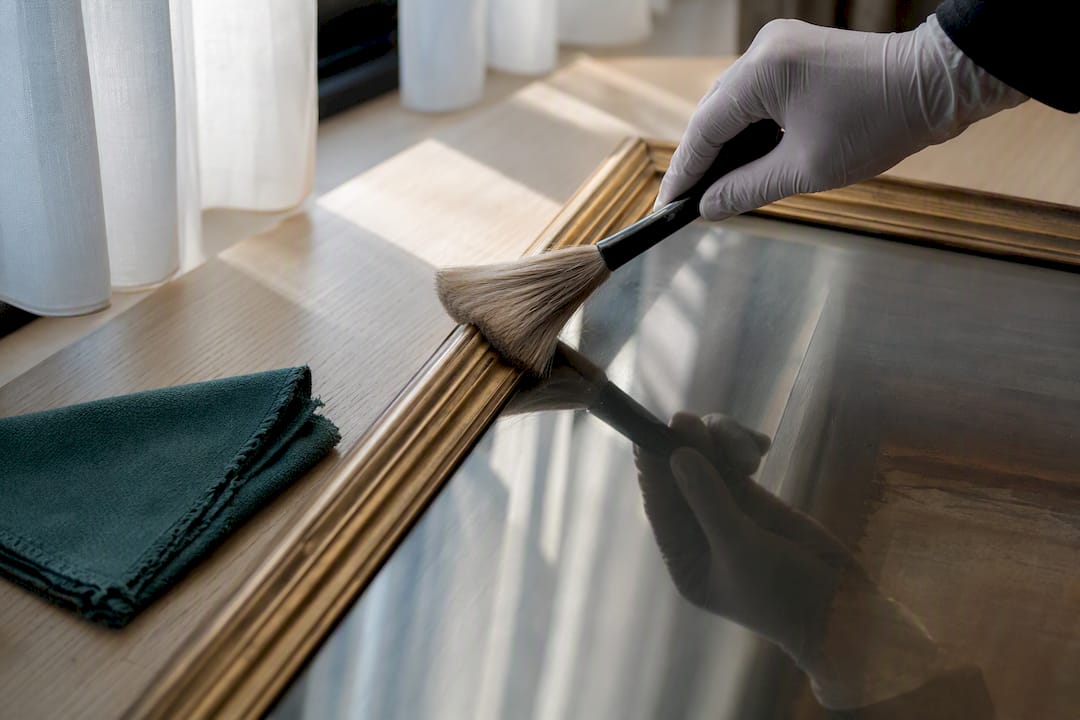 Gloved hand cleaning framed art glazing