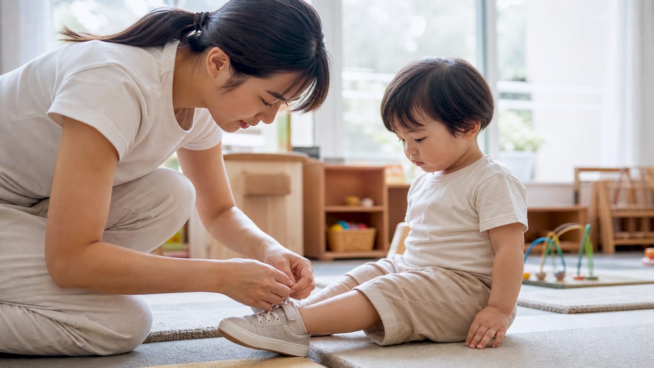Caregiver adjusting toddler’s jacket in nursery