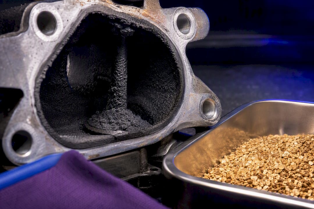 Carbon buildup on an intake valve beside walnut media