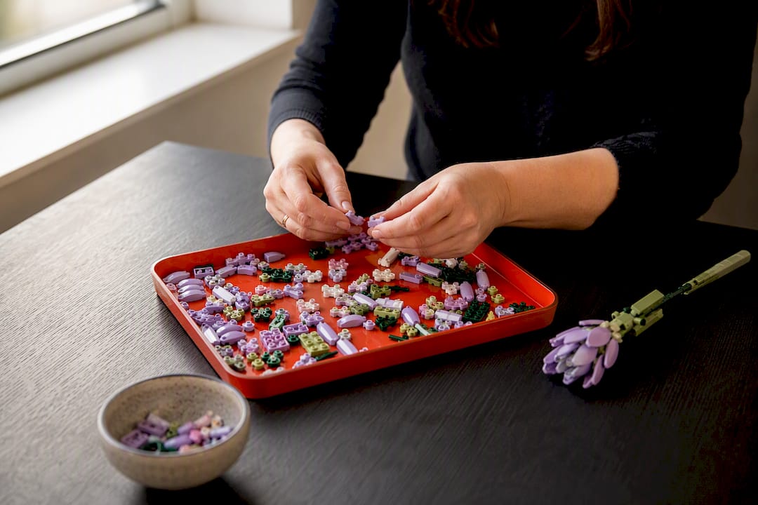 Hands sorting small building pieces in a tray