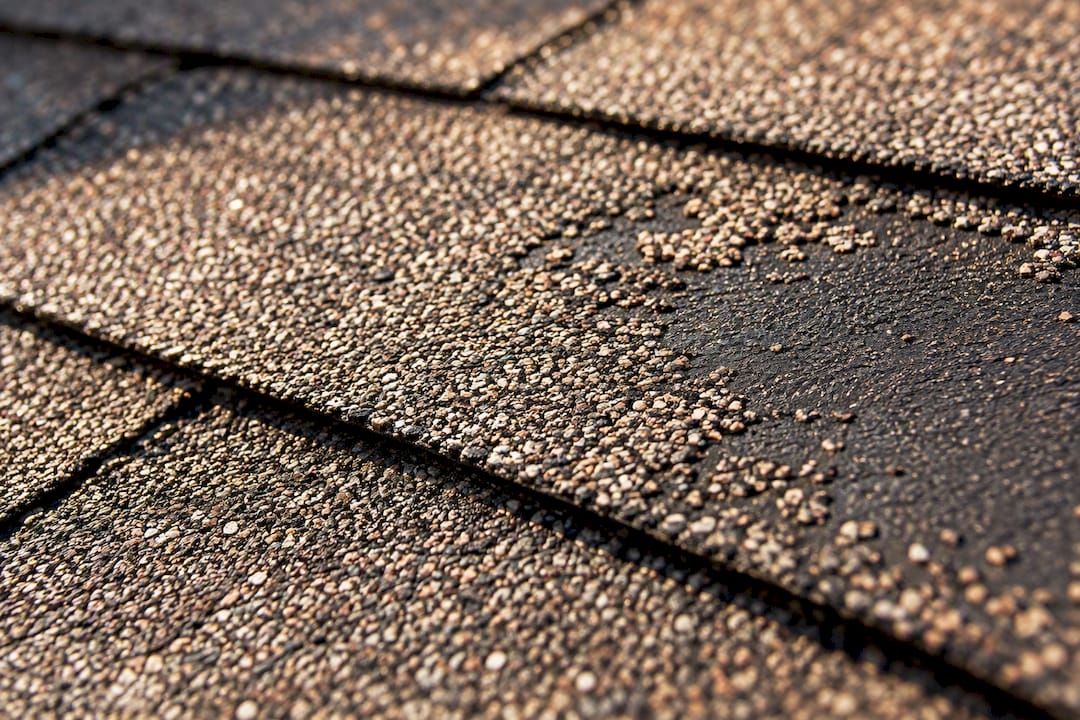 Close view of exposed asphalt beneath lost granules
