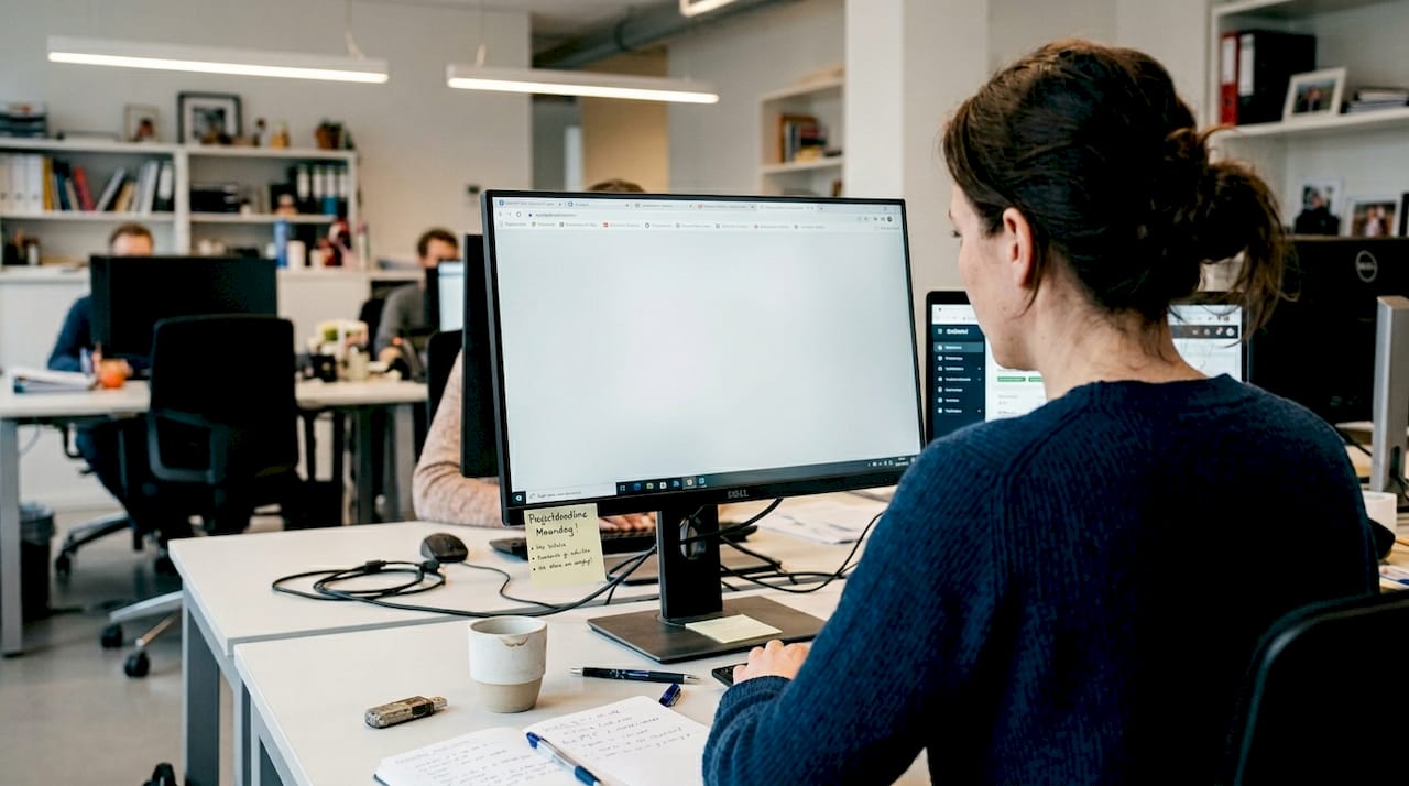 Een medewerker werkt achter zijn bureau met gebruiksvriendelijke software voor flexibel werken.