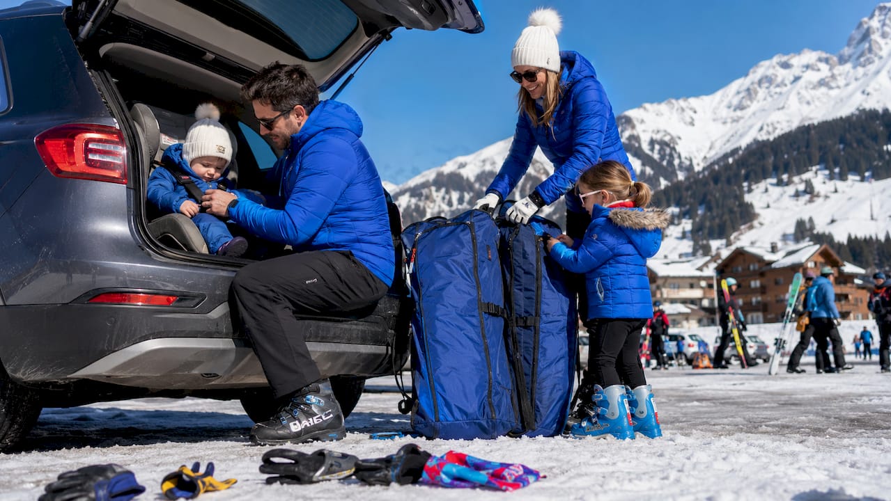 Family preparing car for ski transfer with baby seat and ski bags