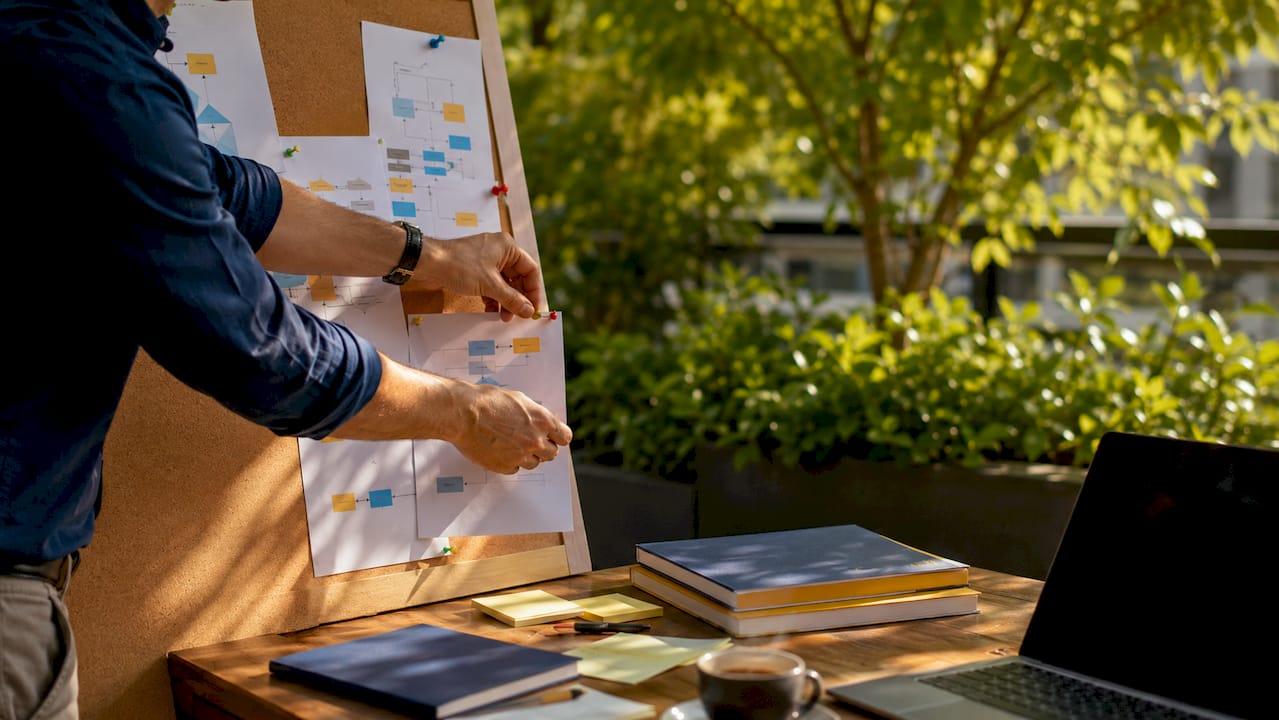 Consultant hands arranging privacy design workflow on corkboard