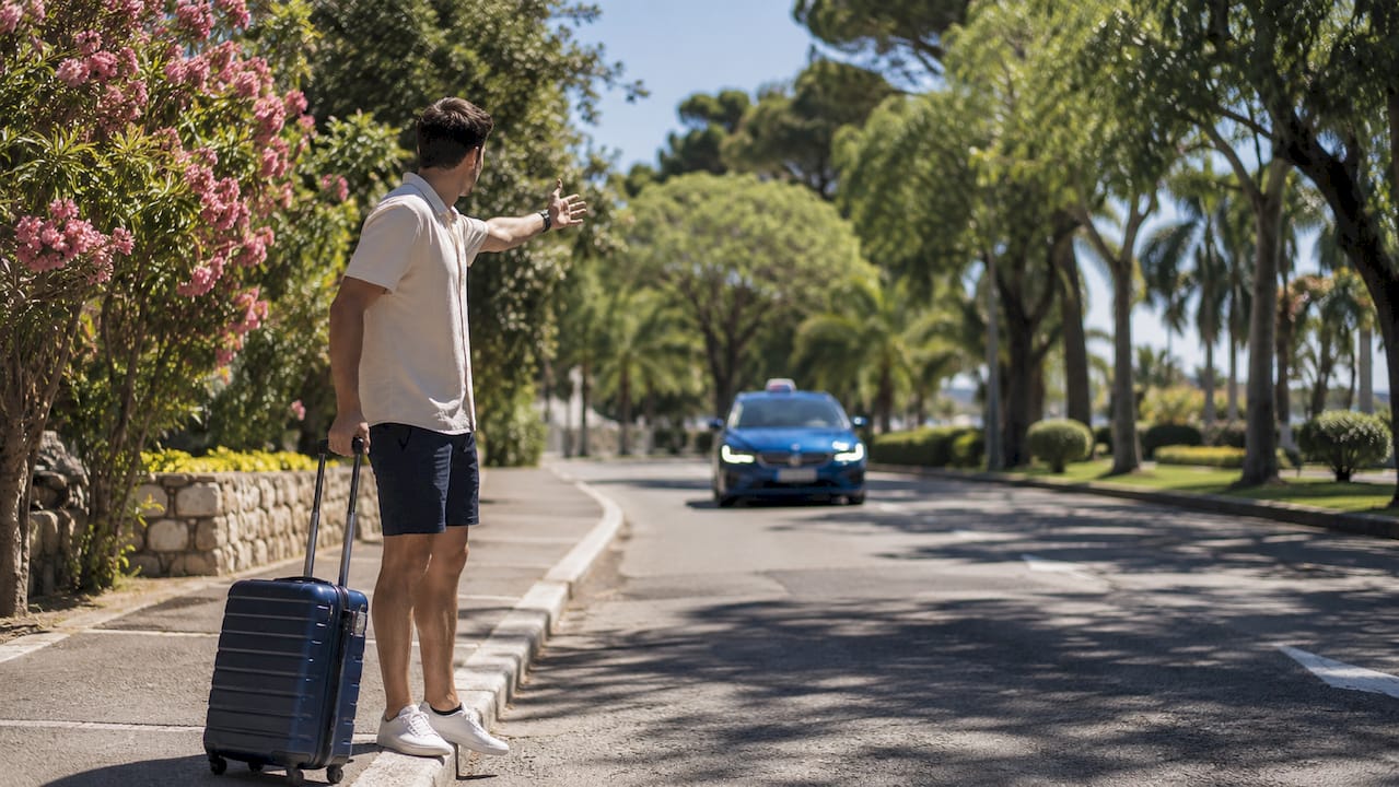 Young man hailing taxi on busy Nice street