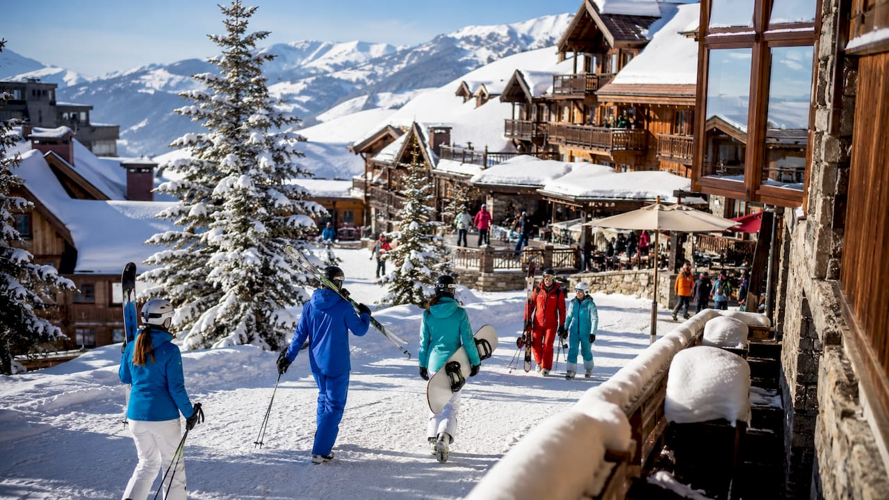 Skiers and chalets in snowy Les Arcs alpine village