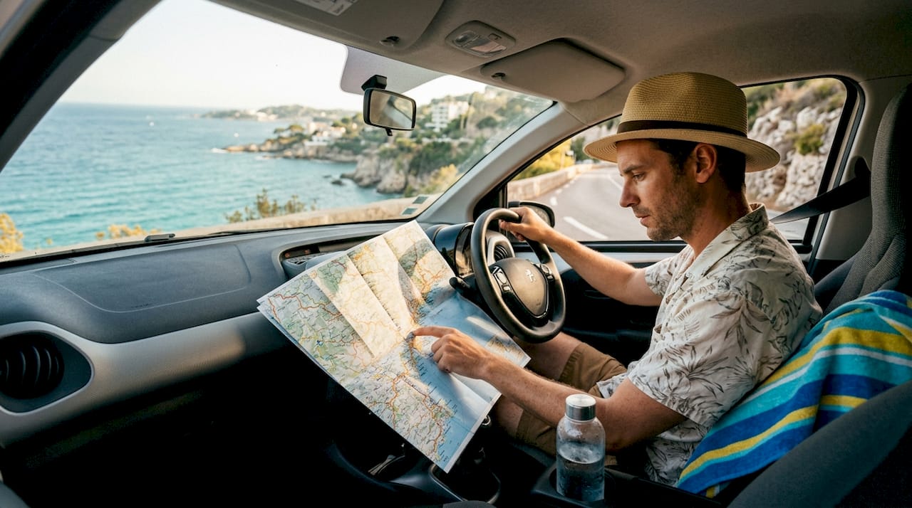 Traveler consulting map in rental car by coast