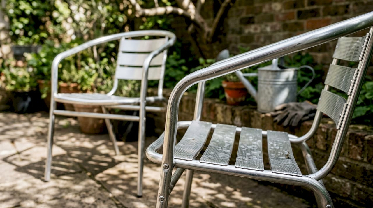 Edelstahlstühle, die von Regenwasser benetzt und von Kratzern gezeichnet sind