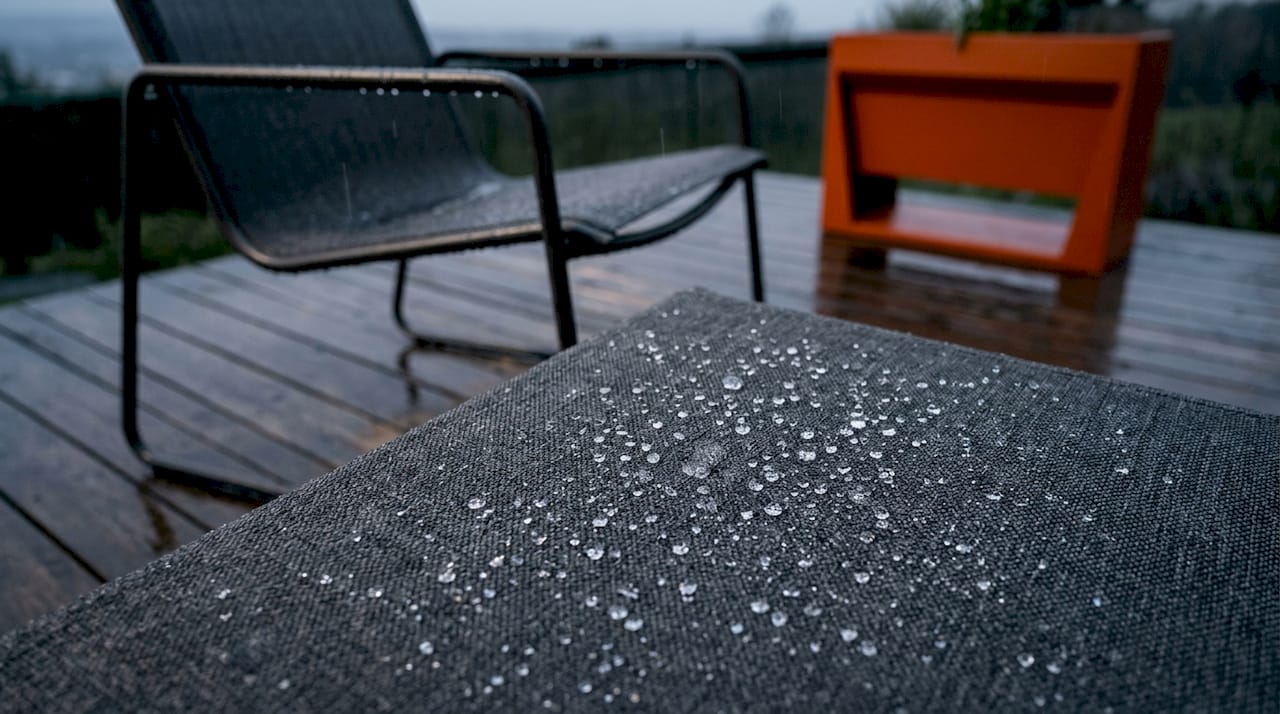 Detailaufnahme eines wetterfesten Outdoor-Polsterstoffs mit sichtbaren Wassertropfen