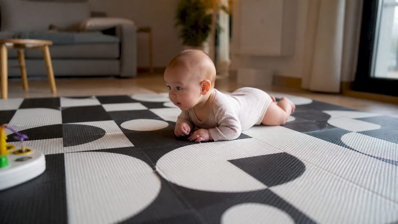 Bauchzeit fürs Baby auf einer bunten Spielmatte