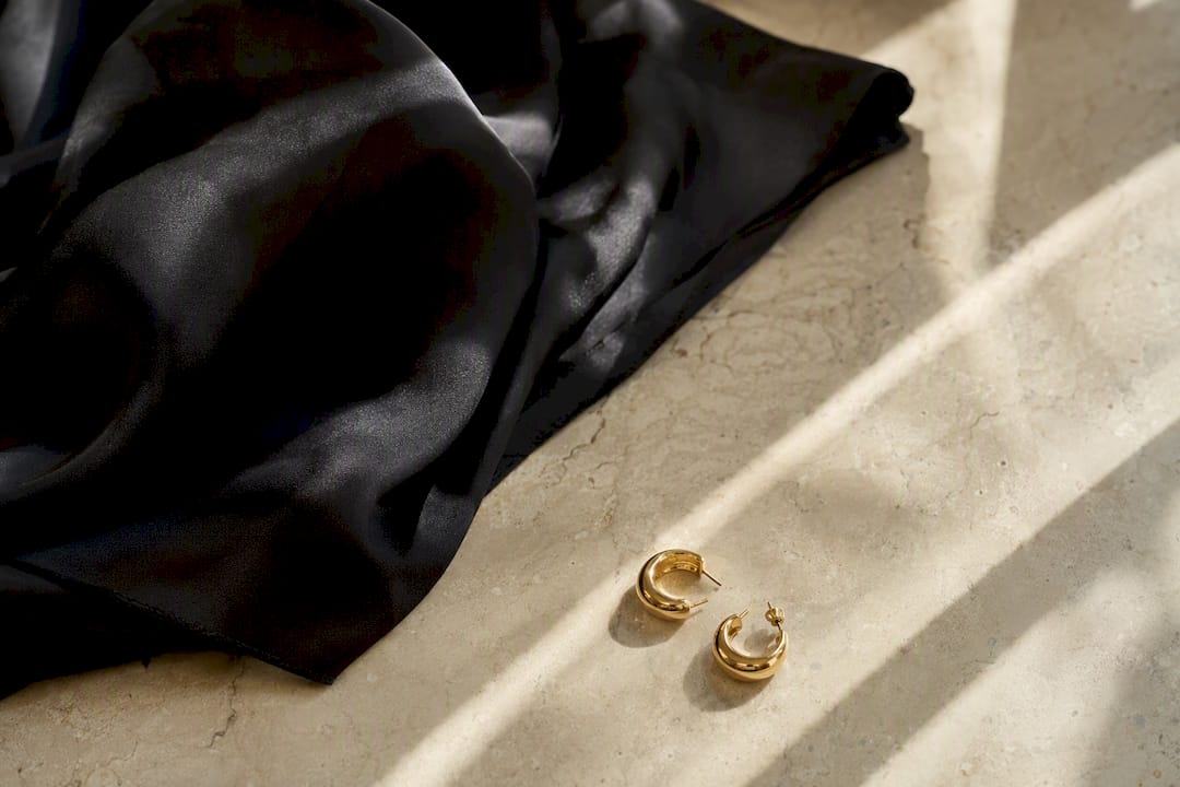 Kontrast von Satin-Schal und goldenen Ohrringen