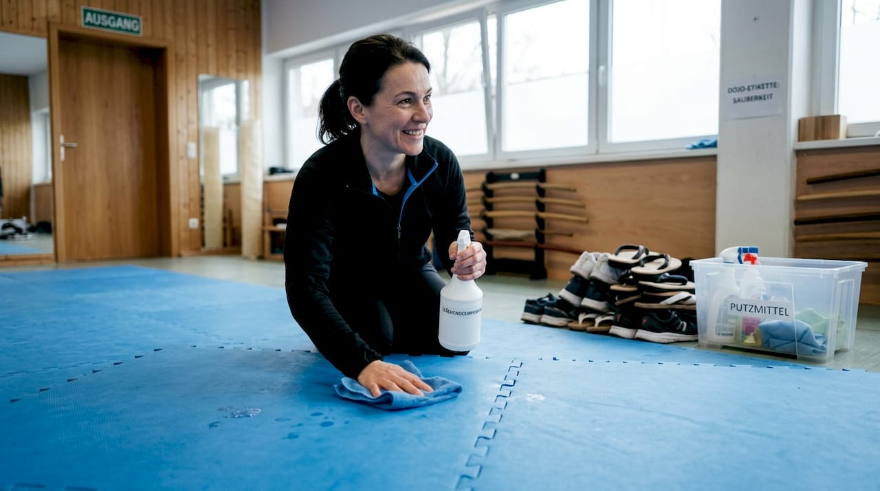 Ein Trainer sorgt dafür, dass die Matten im Dojo gründlich und hygienisch gereinigt werden.