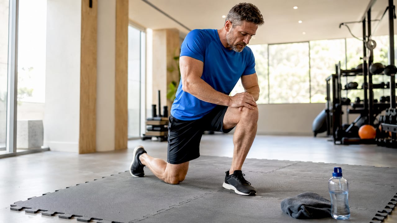 Ein Sportler absolviert Kniebeugen auf einer Trainingsmatte mit Stecksystem.