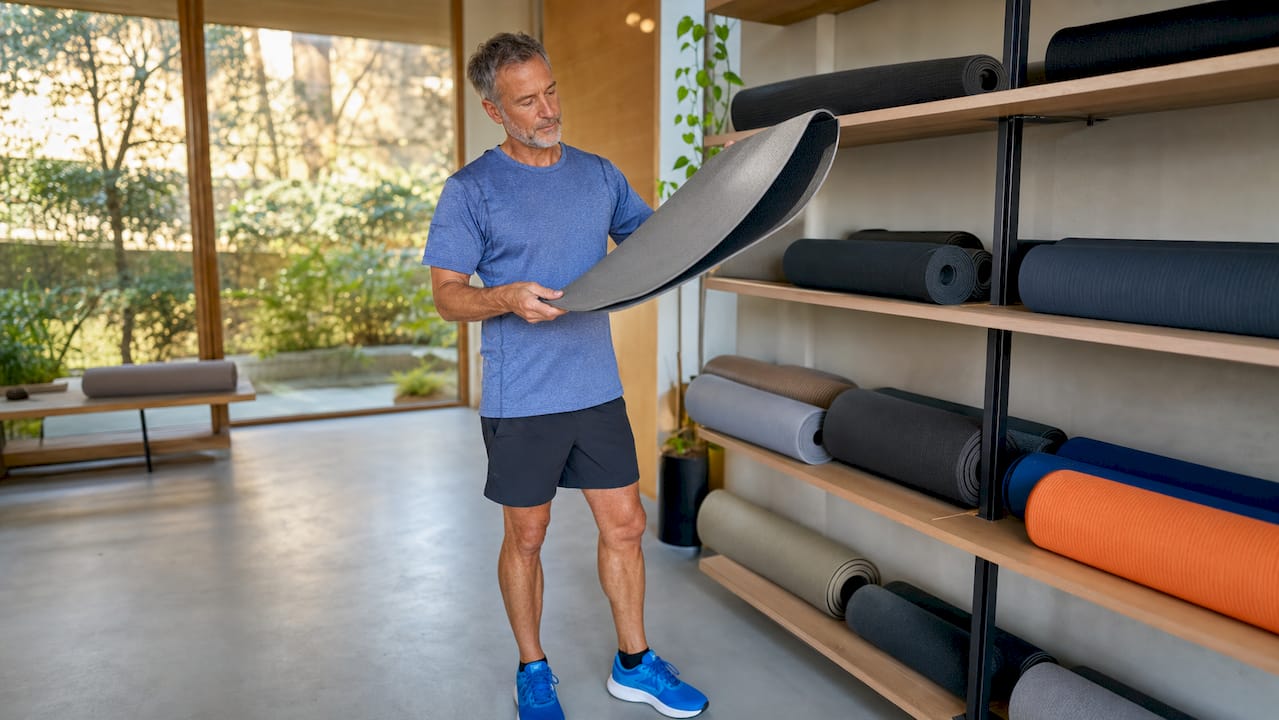Ein Mann testet im Sportladen Fitnessmatten darauf, ob sie keinen unangenehmen Geruch haben.