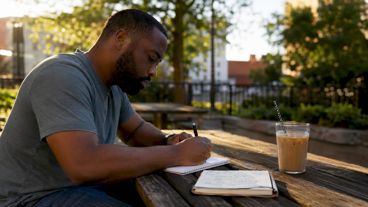 Overhead view of hands taking coding interview notes in coffee shop