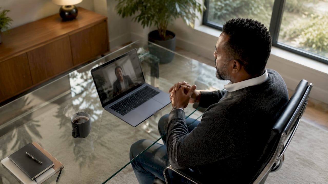 Man engaging in hybrid interview video call at home