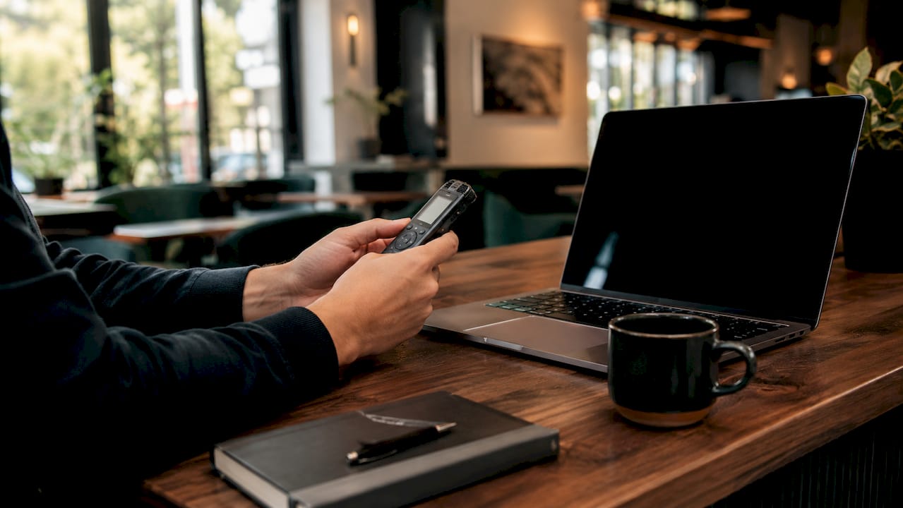 Hands typing with headset and recorder nearby
