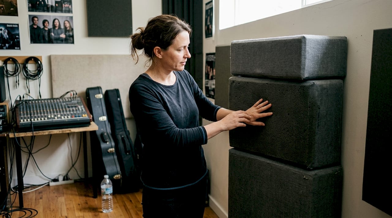 A woman inspects bass straps in the studio.