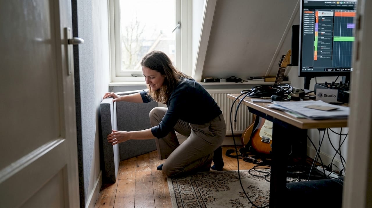 Eine Frau installiert eine Bassfalle, um ein akustisches Problem in einer Ecke zu lösen