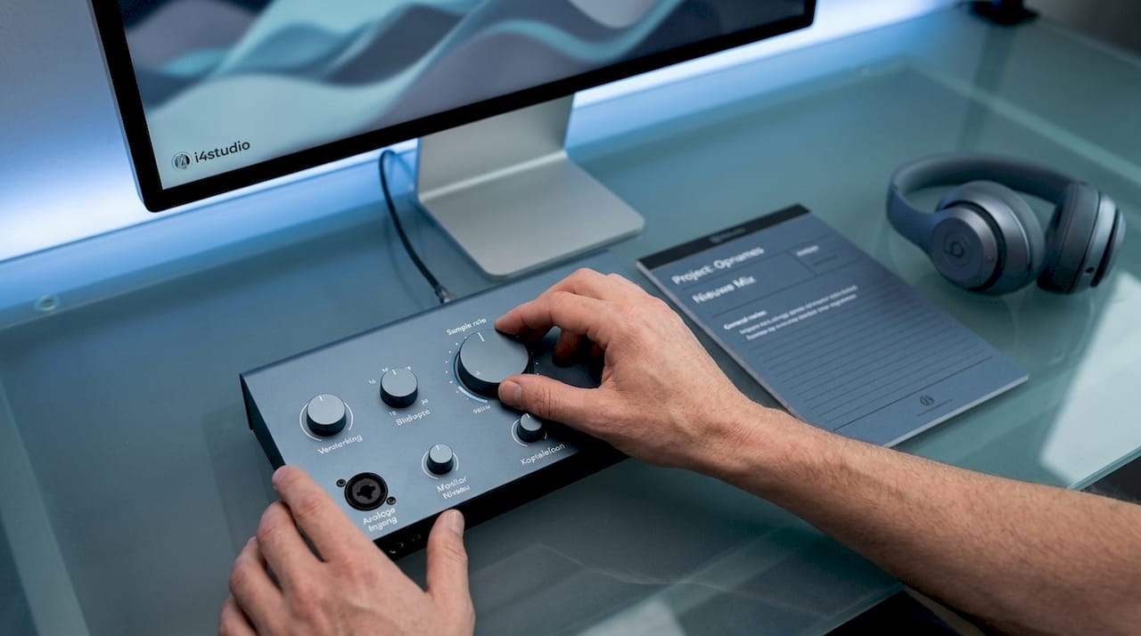 Iemand draait aan de knoppen van een audio-interface om de instellingen te finetunen.