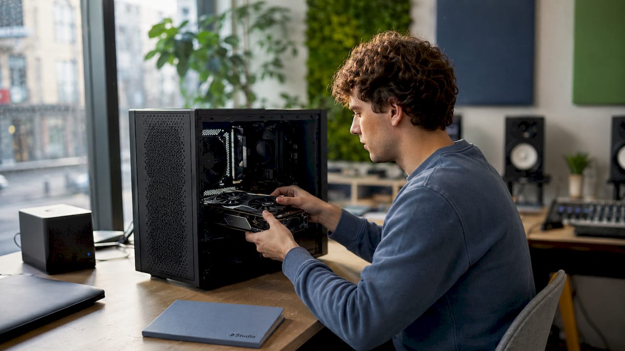 A pair of hands install a GPU in an AI music computer.