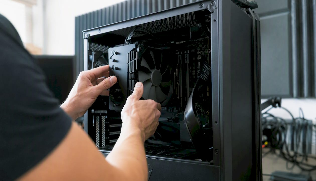 Mit beiden Händen wird der geräuscharme Lüfter des Computers vorsichtig justiert.