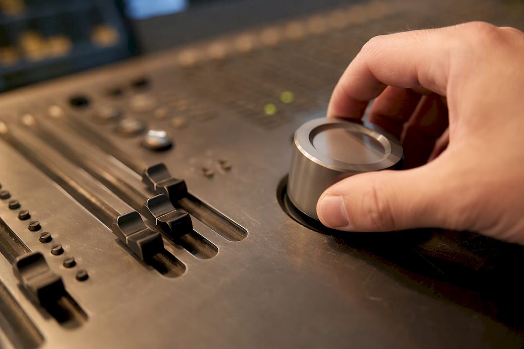 Hand draait aan metalen potentiometer van studiodevice