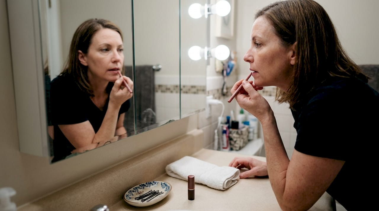 Middle-aged woman using lip liner in bathroom