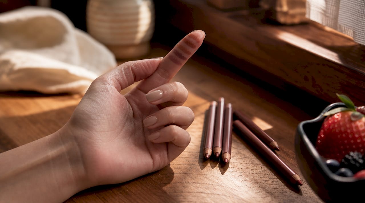 Close-up swatches of brown lip liners on fingertip