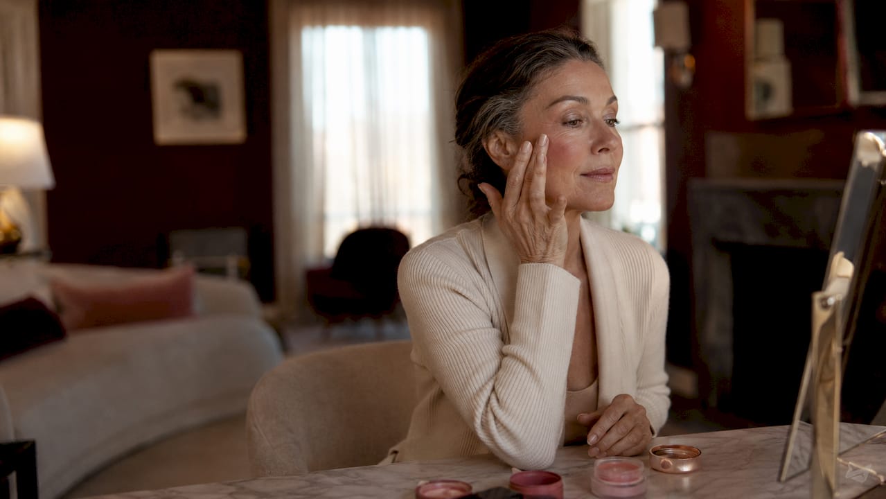 Close-up of mature woman applying cream blush