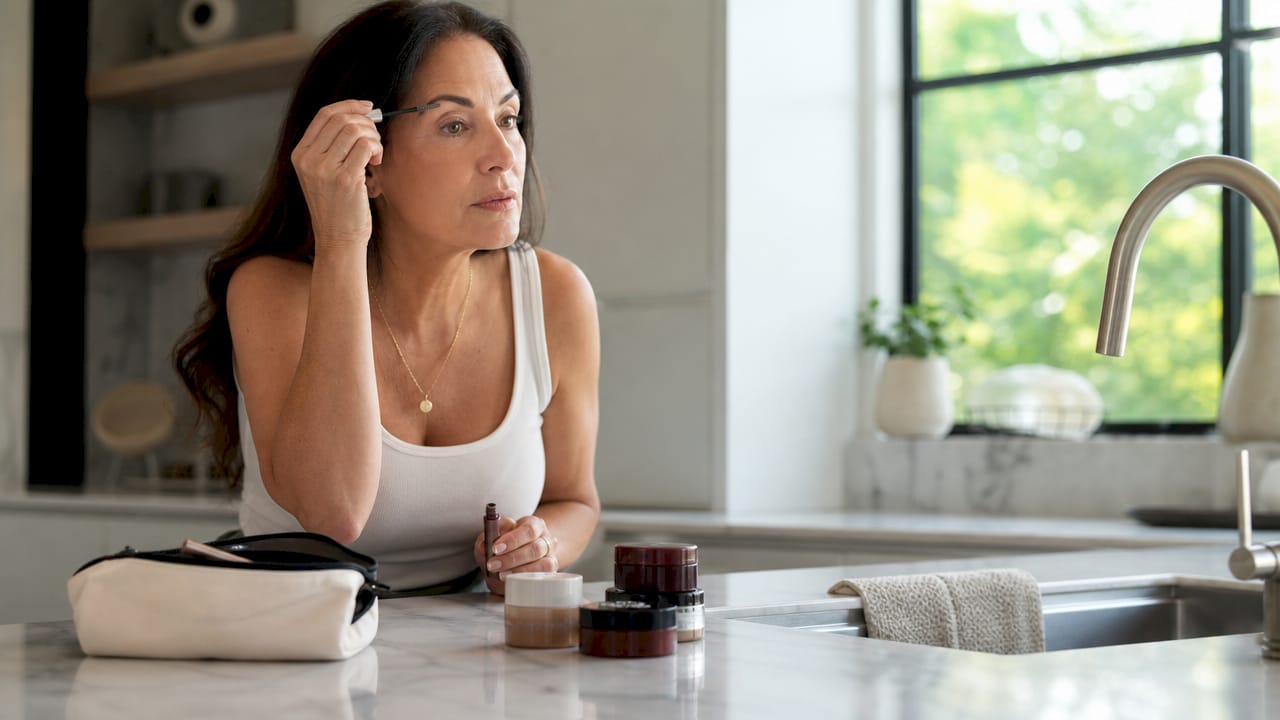 Woman applying tinted brow gel in bathroom