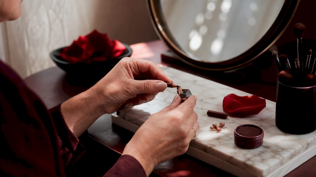 Hands sharpening lip liner pencil on makeup desk