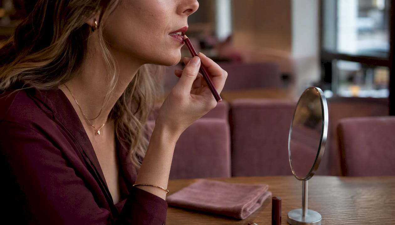 Woman applying black lip liner with pencil