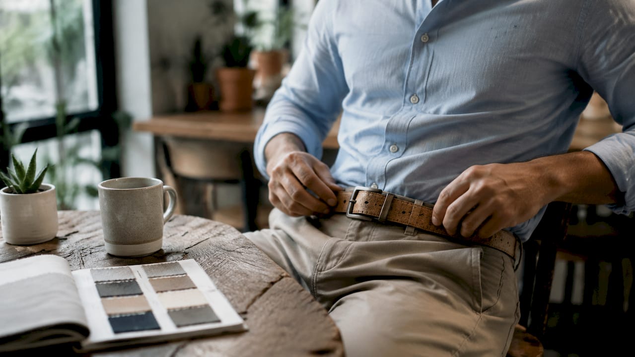 Hands adjusting cork belt in professional office setting