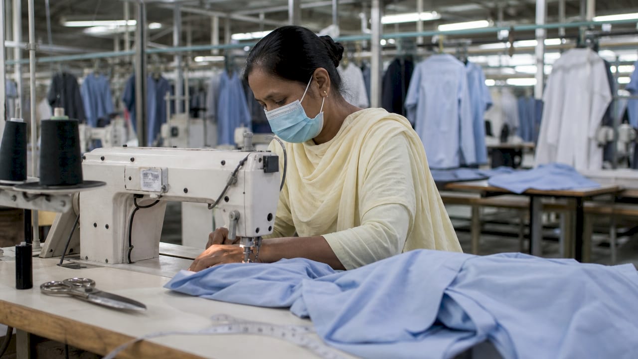 Garment worker sewing fabric in factory