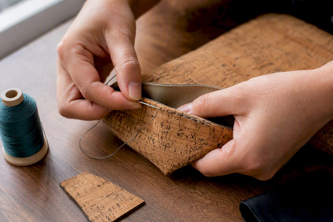 Hands repairing a loose cork accessory stitch