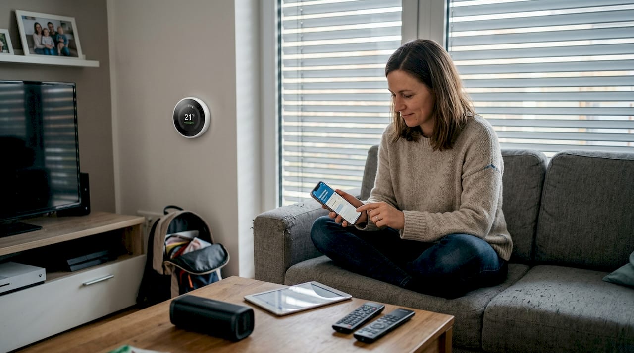 Gebäudeinstallation Elektro: Smarte Lösungen für Haushalt 2 Im Wohnzimmer steuert eine Frau ihre Smart-Home-Geräte und genießt den Komfort moderner Technik.