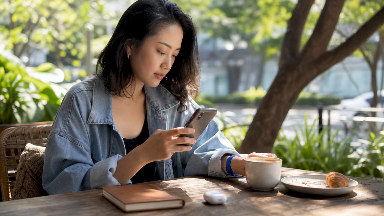 Asian performer casually working on smartphone at café