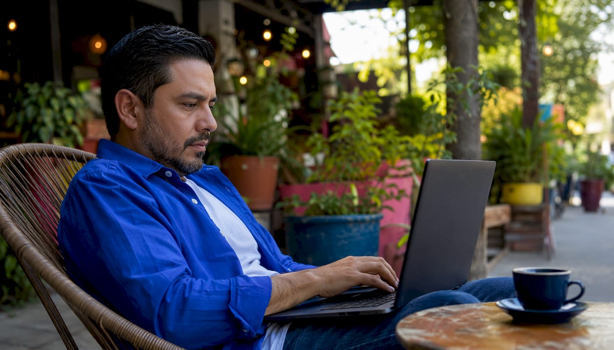 Hispanic man typing on laptop at startup office desk