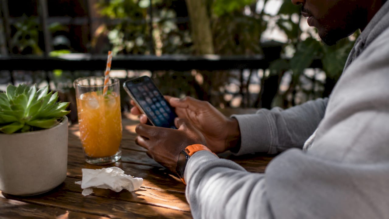 Hands holding smartphone in café with social apps