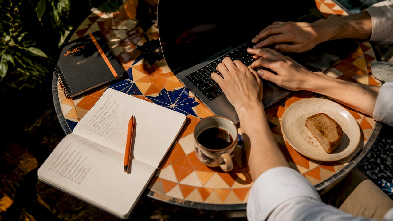 Hands typing hashtags on laptop at café table