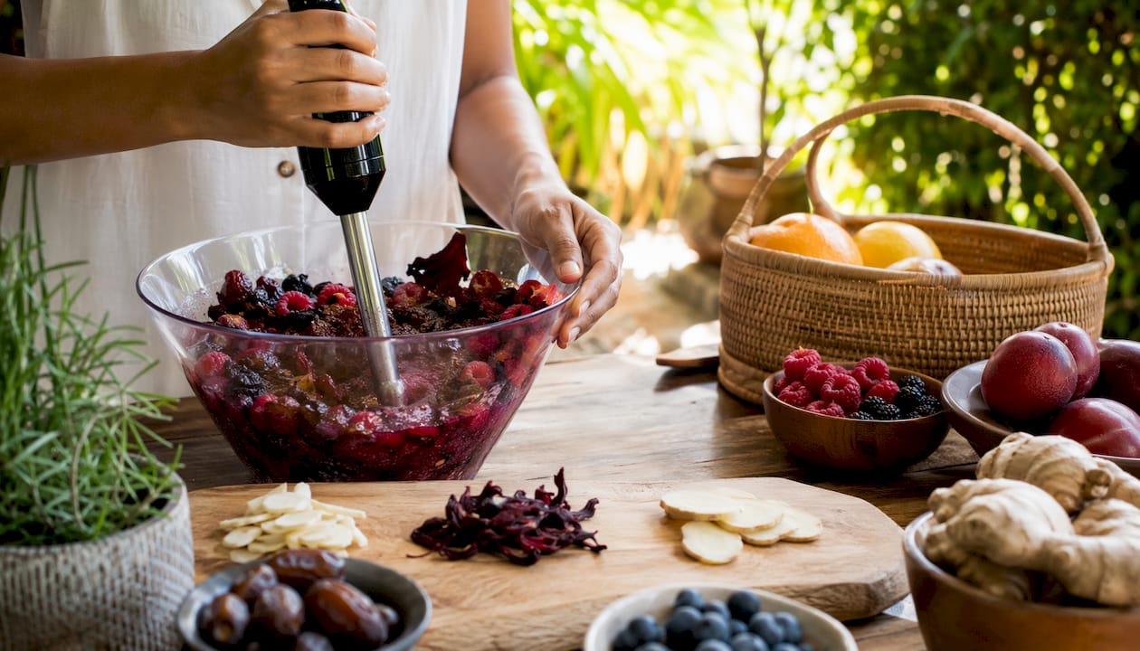 Hands preparing botanical smoothie with berries