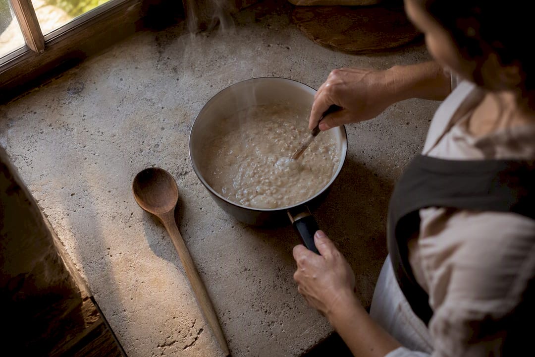 Hands stirring egg whites into oatmeal porridge