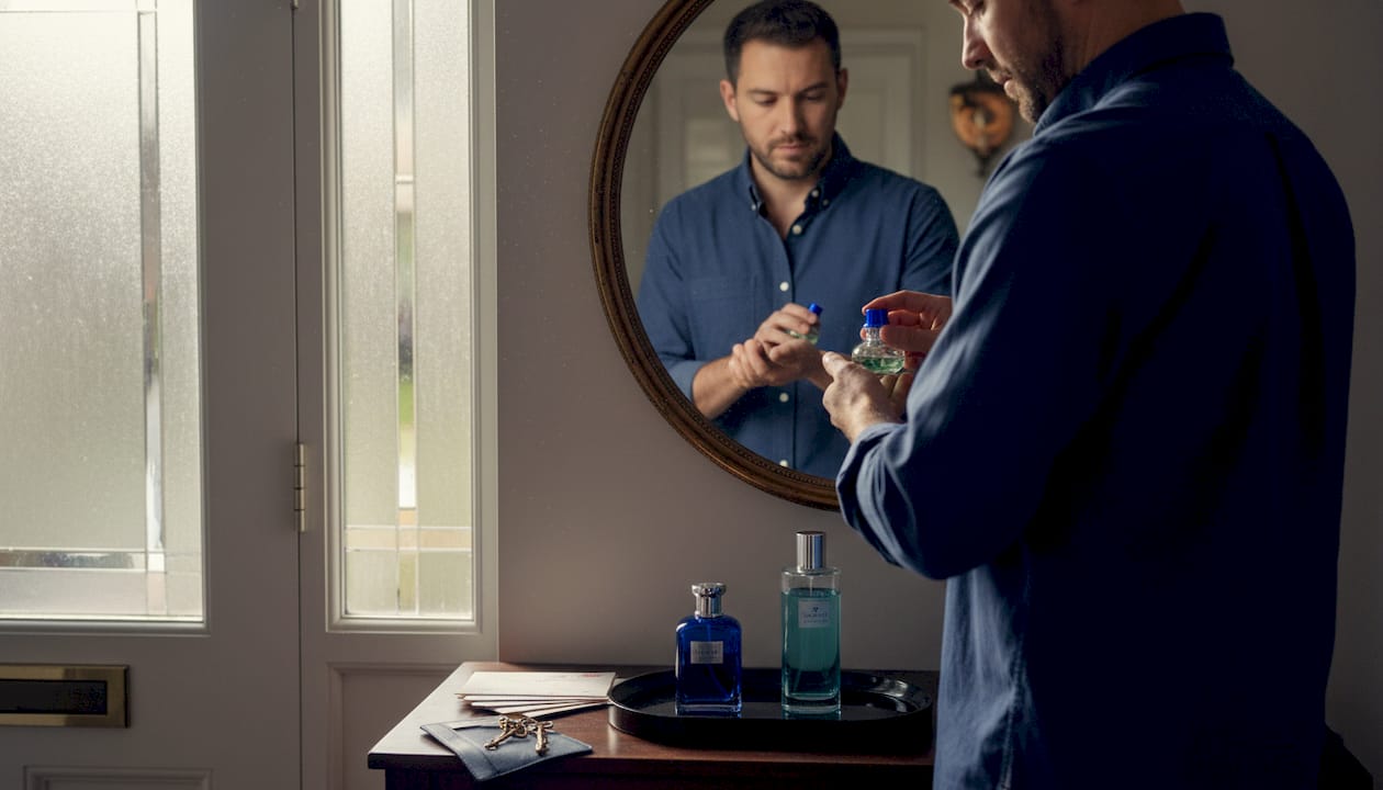 Man applying perfume in entryway mirror