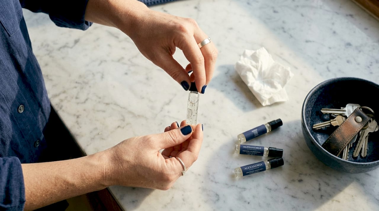 Unas manos destapando una muestra de perfume