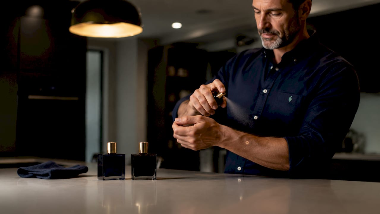Man applying layered cologne on wrist close-up