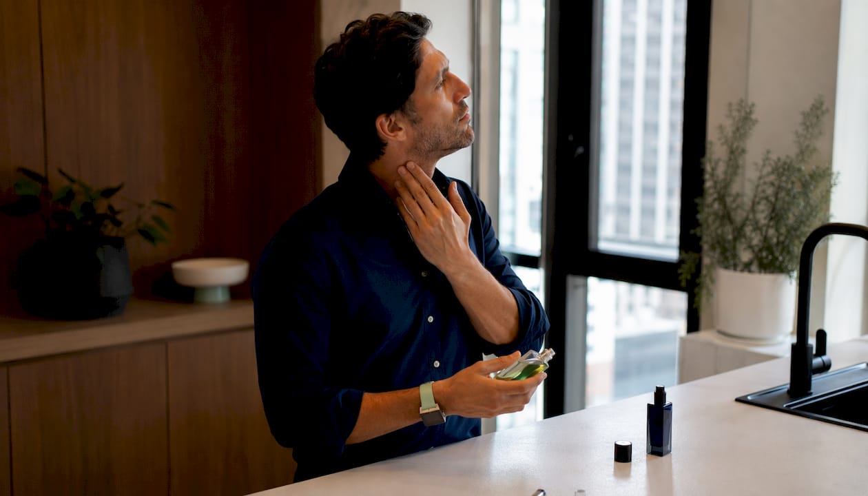 Man applying body oil before perfume layering