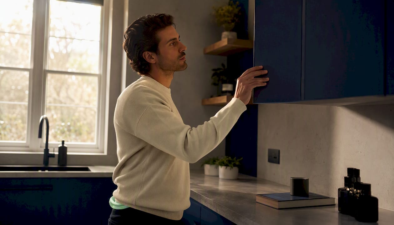 Man closing wardrobe avoiding sunlight on cologne bottles