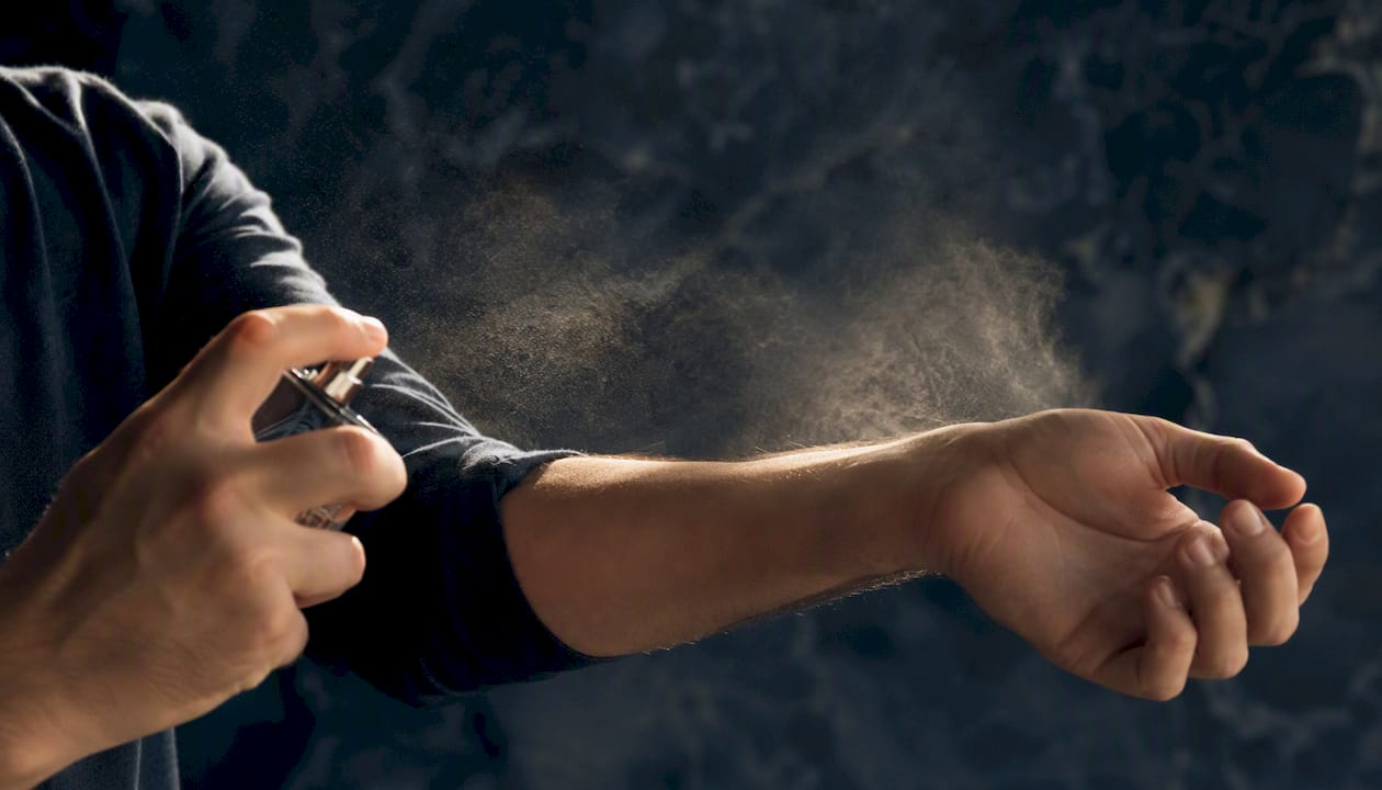 Man spraying cologne on wrist pulse points