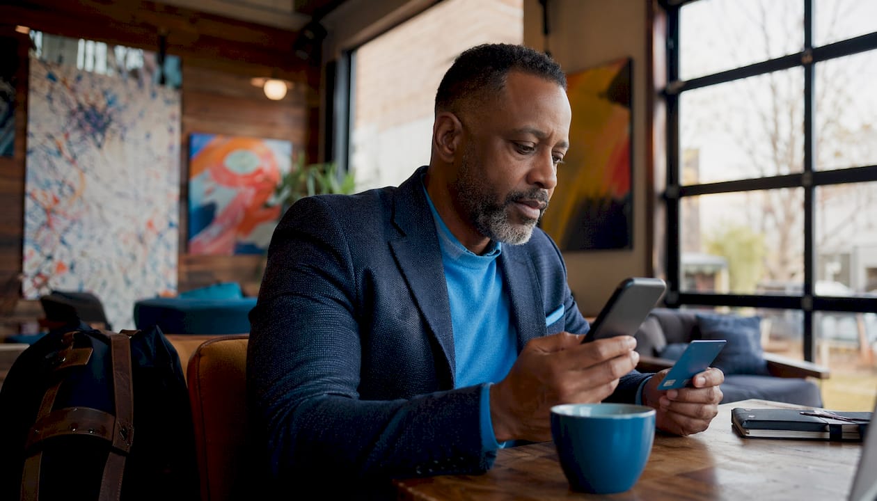 Businessman checking hotel perks on smartphone in lobby